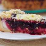 Ein Stück des Streuselkuchen mit Apfelbeerenfüllung und Cremeschicht unten drunter.