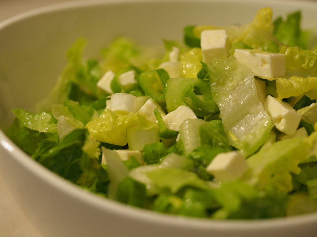 Romana Salat mit Frühlingszwiebel und Hirtenkäse angemacht mit etwas Olivenöl und Zitronensaft und -abrieb