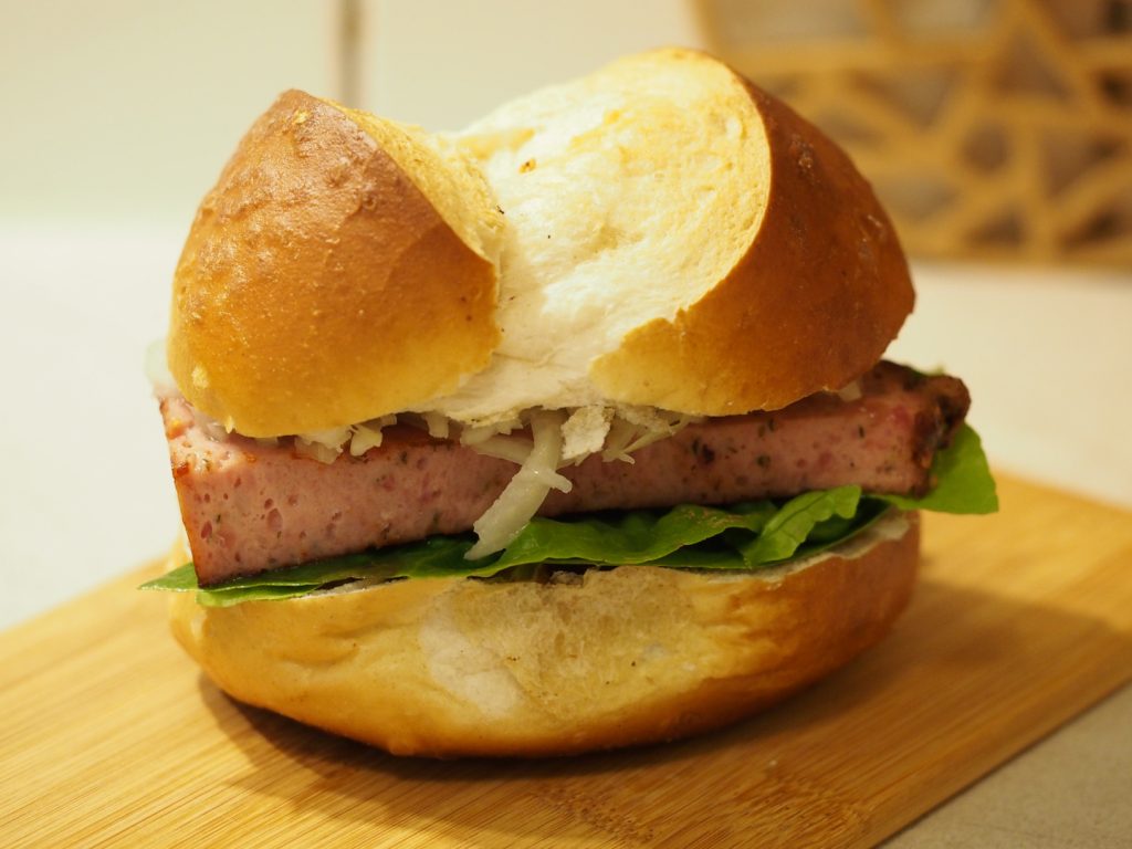 Der Leberkäswecken mit süßem Senf, Salat und Krautsalat im Laugenwecken.