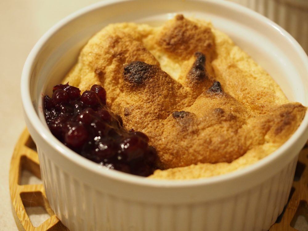 Eine sehr kleine Portion Salzburger Nockerl mit ein paar Löffel Preiselbeeren an der Seite.