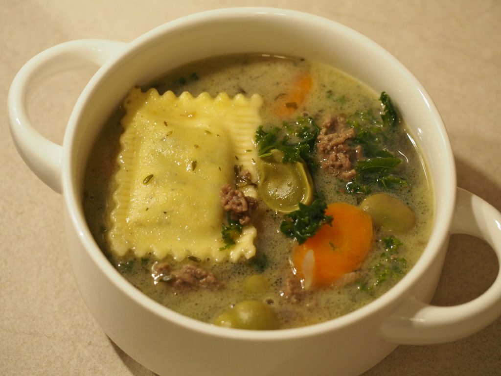 Eine Suppentasse gefüllt mit dem Eintopf mit Puffbohnen, Grünkohl, Karotten, Hackfleisch und Maultaschen