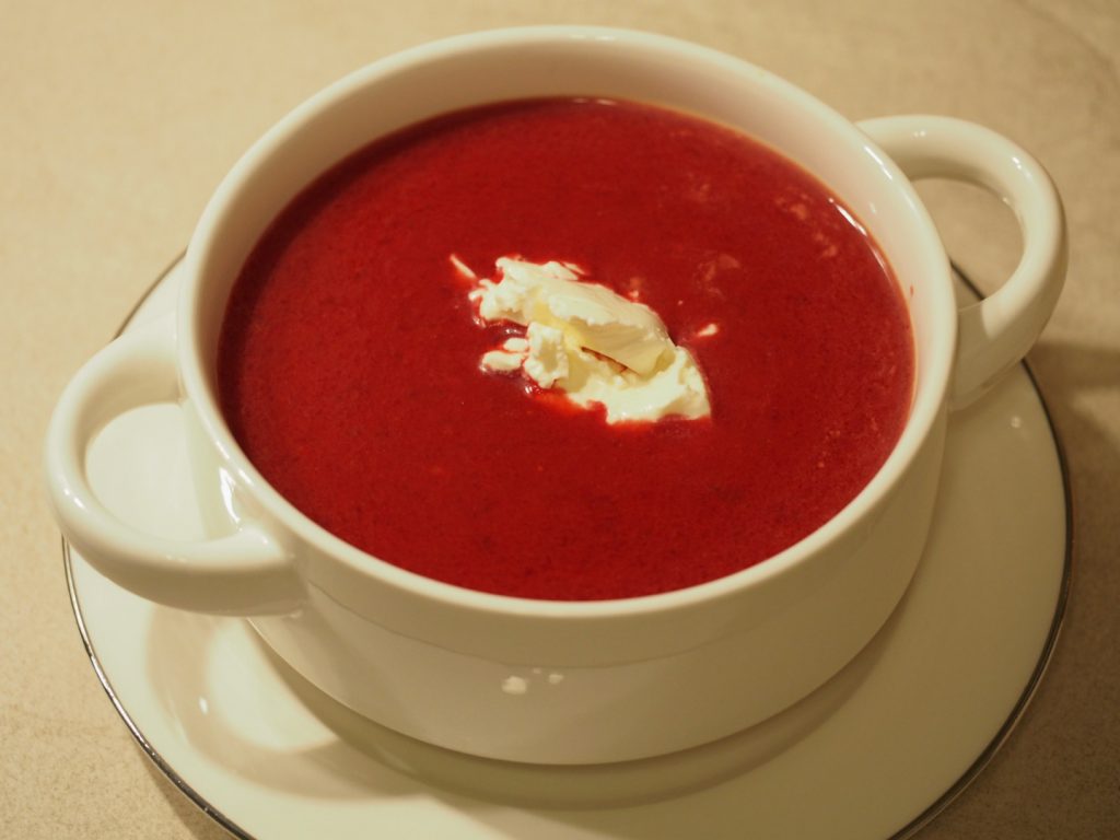 Eine Suppentasse mit einer rote Bete Suppe. In der Mitte ist ein Klecks Schmand.