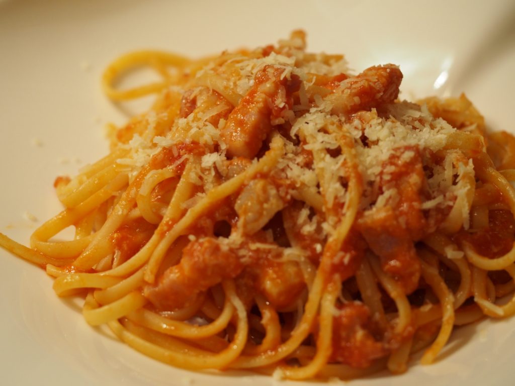 Eine Portion der Pasta Amatriciana, bestehend aus Tomatensauce, Bauchspeck und Hartkäse, auf einem Teller