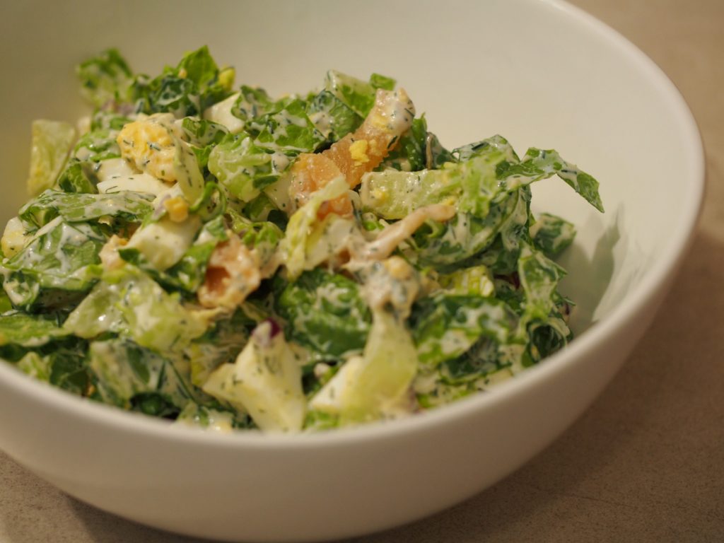 Salat mit Eiern und Räucherlachs in einer weißen Schüssel