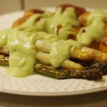 Gebackene Kartoffeln und grüner und weißer Spargel auf einem Teller. Über beidem wurde großzügig die Avocadosauce gegeben.