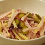 Eine Portion des Schweizer Wurstsalat mit Fleischwurst, Emmentaler, Cronichons und roter Zwiebel