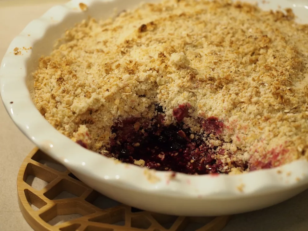 Der fertige Apfelbeeren-Birnen Crumble aus dem bereits eine Portion entnommen wurde.