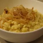 Eine Portion Käsespätzle mit einigen geschmelzten Zwiebeln oben drauf
