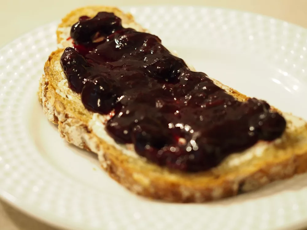 Ein Kürbiskernbrot bestrichen mit Margarine und der Marmelade