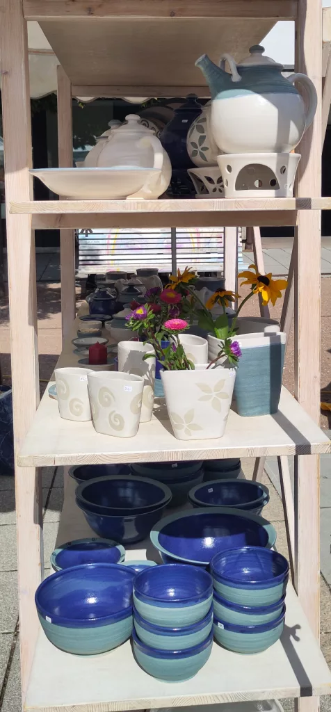 Ein Regal mit blau-türkisen Schalen, weißen Bechern und Teekannen mit passendem Stövchen