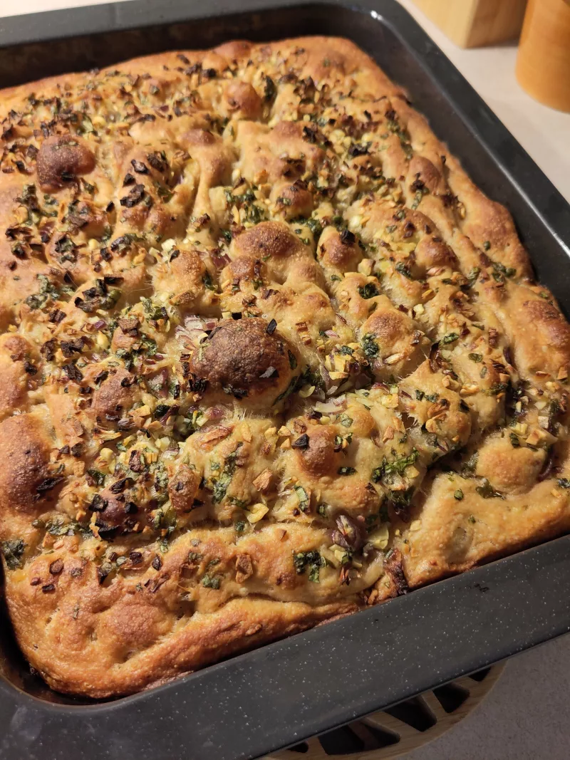 Das fertig gebackene Focaccia noch in der Form. Man sieht, dass der Teig Blasen gebildet hat und gold-braun gebacken wurde.