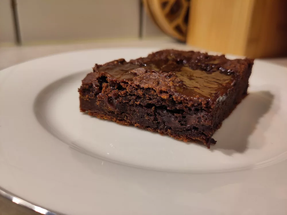 Ein nicht dekoriertes Stück Brownie auf einem Teller.