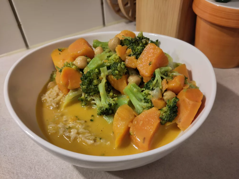 Eine weiße Schüssel gefüllt mit einer Portion Reis, auf der das Gemüsecurry gegeben wurde.