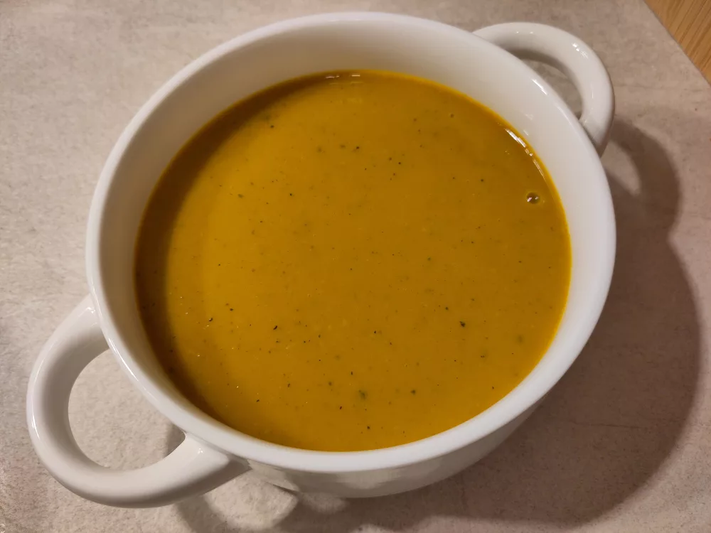 Eine weiße Suppentasse gefüllt mit einer Kürbissuppe