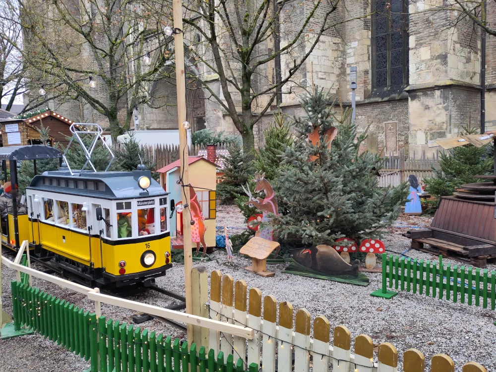 Ein Straßenbähnle in einem abgezäunten Bereich, der mit Märchenszenen gestaltet wurde.
