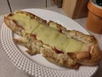 Ein zubereitetes Raclette-Baguette gefüllt mit Rohschinken und Raclette Käse.