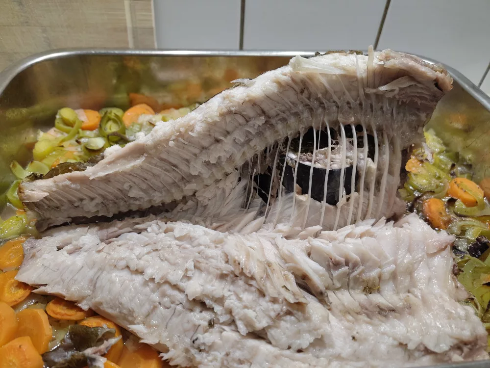 Ein Seitenfilet des Fisches wurden an der Mittelgräte entlang nach unten weggeklappt. Damit wird die Sicht auf die Tasse frei, die den Fisch aufrecht gehalten hat.