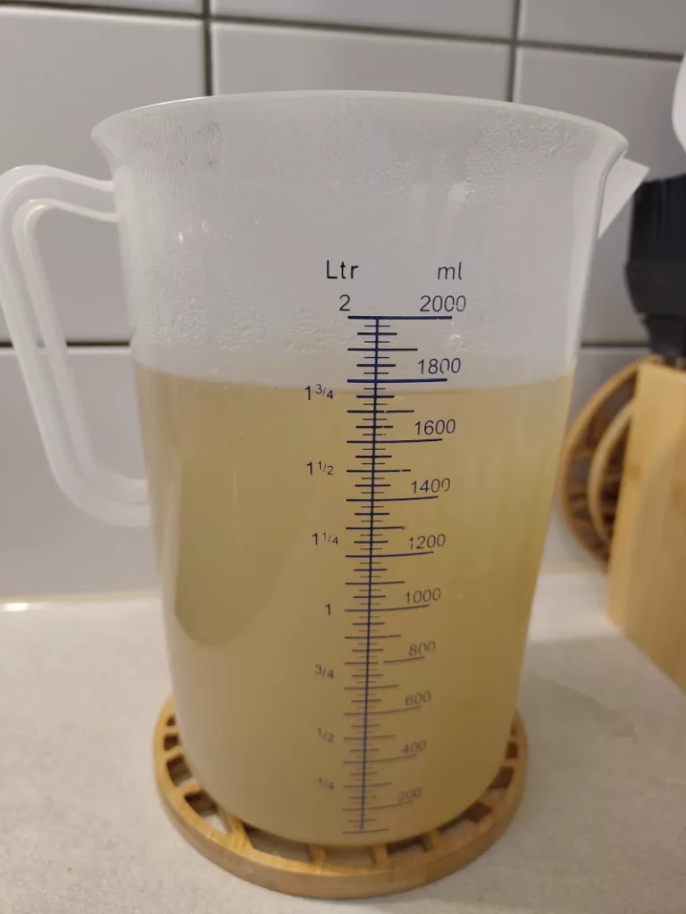 Der fertige Fischfond wurde durch ein Sieb in einen großen Messbecher gegossen.