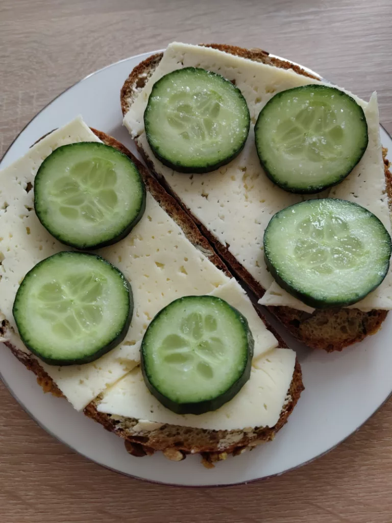 Zwei Brotscheiben belegt mit Tilsiter Käse und Gurkenscheiben