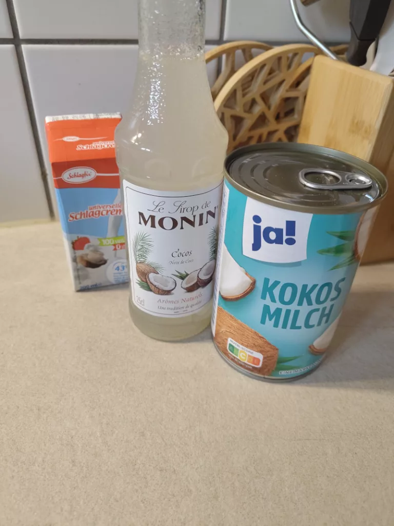 Die Zutaten für eine Kokoseiscreme: eine Dose Kokosmilch, vegane Sahne, Kokossirup. Nicht auf dem Bild: Zucker