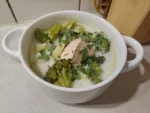 Eine Portion der Suppe aus Brokkoli, Kartoffeln und Lachs in einer weißen Suppentasse