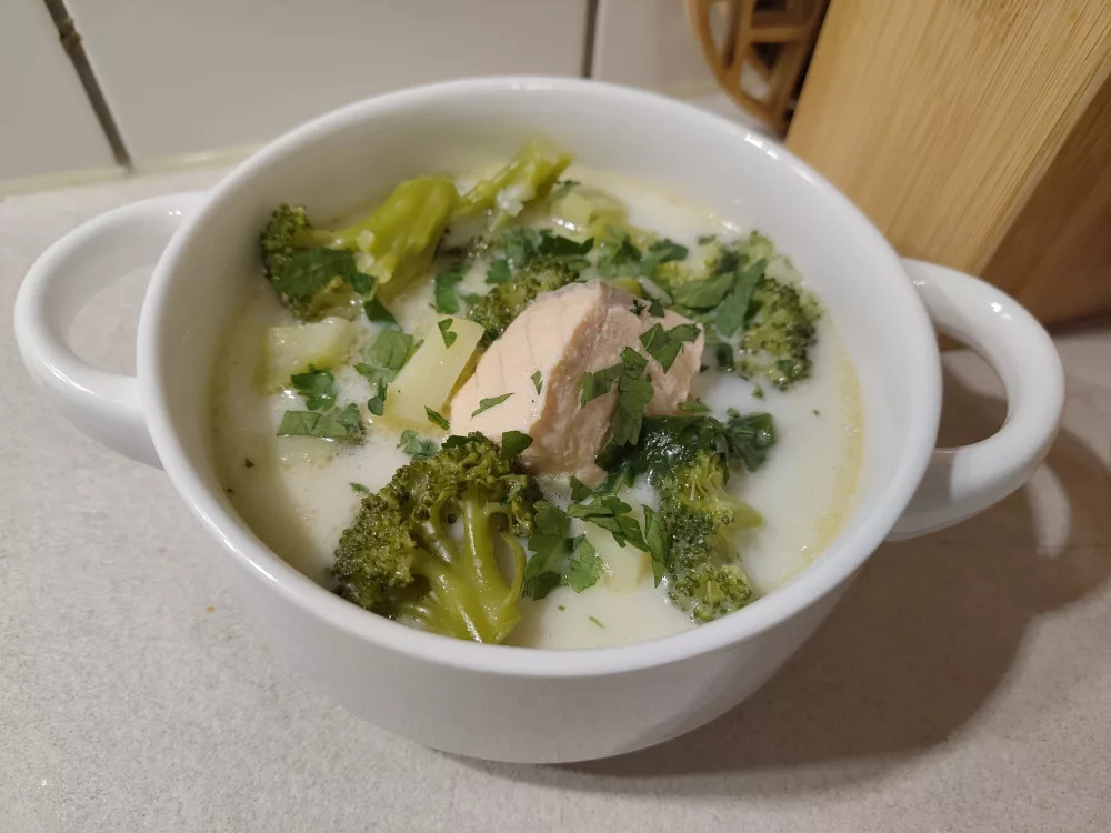 Eine Portion der Suppe aus Brokkoli, Kartoffeln und Lachs in einer weißen Suppentasse