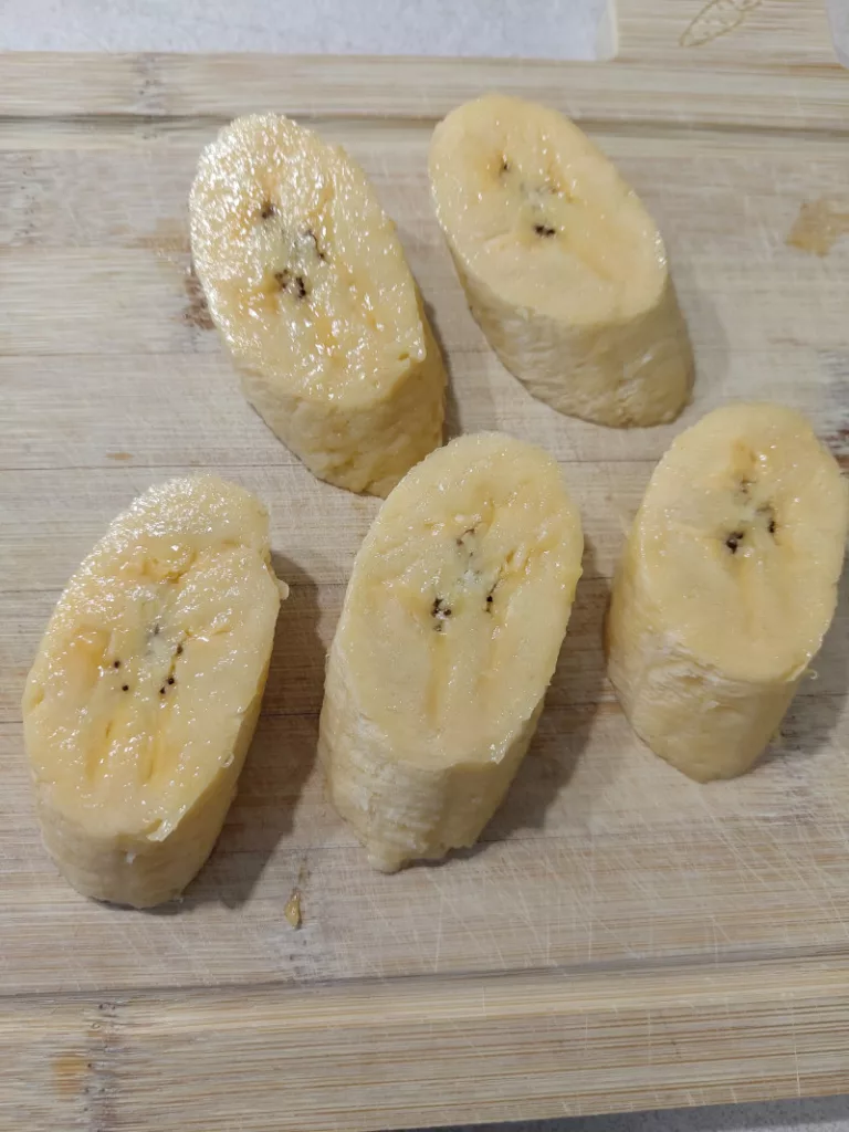 Die vollreife Kochbanane wurde in Scheiben geschnitten. In Konsistenz und Aussehen unterscheidet sie sich nun nur noch wenig von einer Dessert-Banane