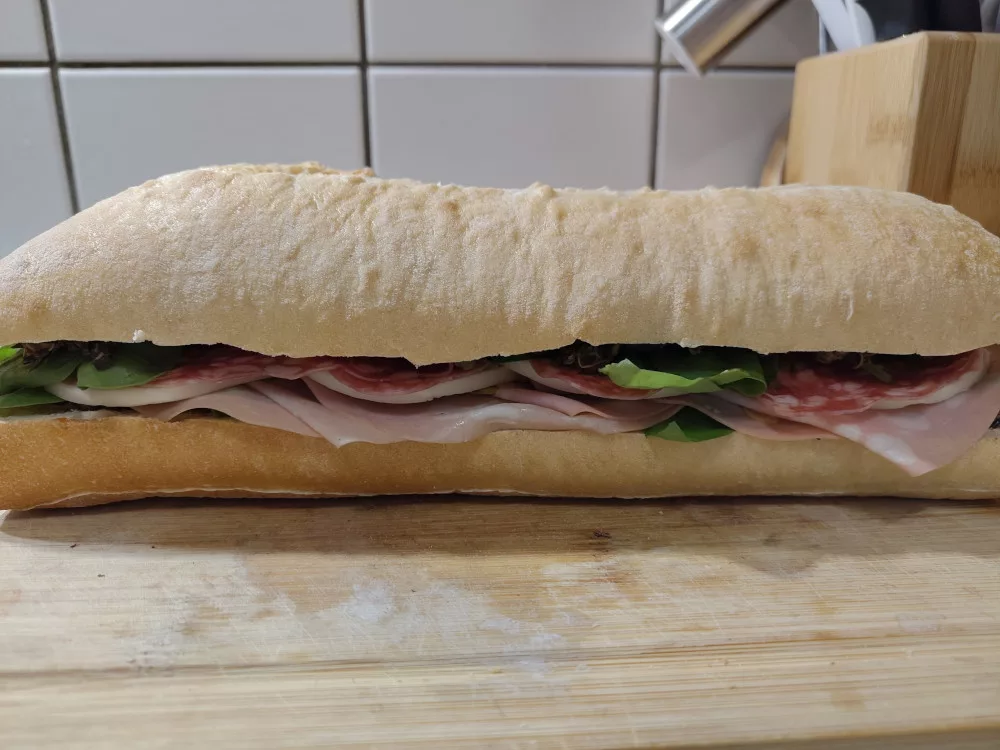 Das fertige Sandwich liegt auf einem Holzbrett