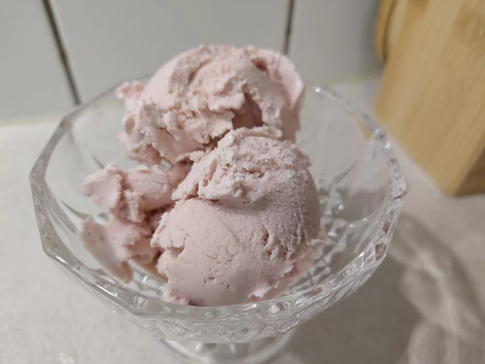 Eine Portion aus 2-3 Kugeln der veganen Rhabarber-Eiscreme. Die Eiscreme hat einen zart-rosa Farbton