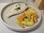 Eine gebratene Scholle mit Salbeibutter neben gekochten Kartoffeln und Karotten