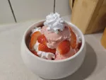 Ein gut gefülltes Schüsselchen mit Erdbeer-, Vanilleeiscreme, vegane Sahne und frischen Erdbeeren.