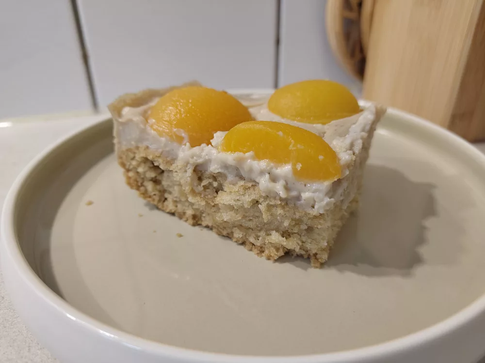 Ein Stück des Rührkuchens mit Vanillepudding und Aprikosen auf einem Kuchenteller.