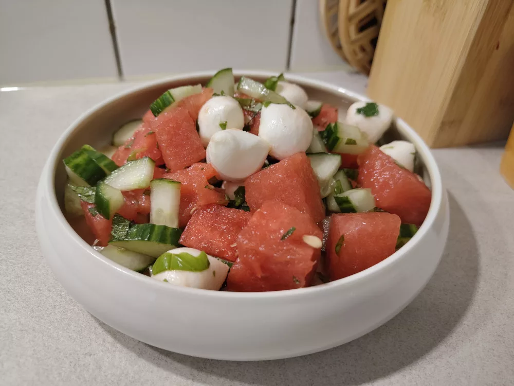 Eine große Portion des Wassermelonen-Gurken Salats mit Mozzarella. Man sieht auch die gehackte Minze und den Basilikum.