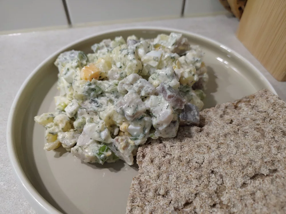 Eine Portion des Matjessalats mit Eiern und viel Dill neben zwei Scheiben Knäckebrot