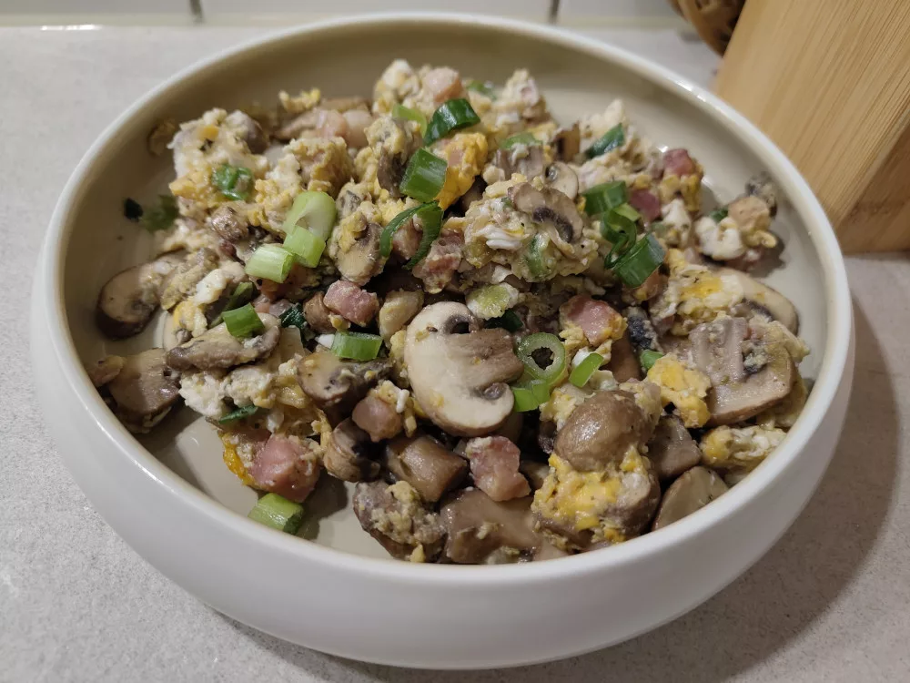 Eine großzügige Portion Rührei mit Bacon, Champignons und Frühlingszwiebel