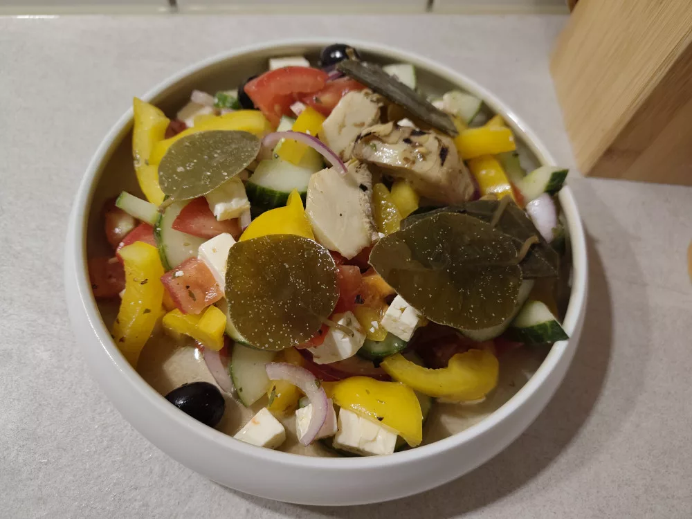 Eine große Portion des griechischen Bauernsalats, der mit Artischockenherzen ergänzt und mit Kapernblättern garniert wurde