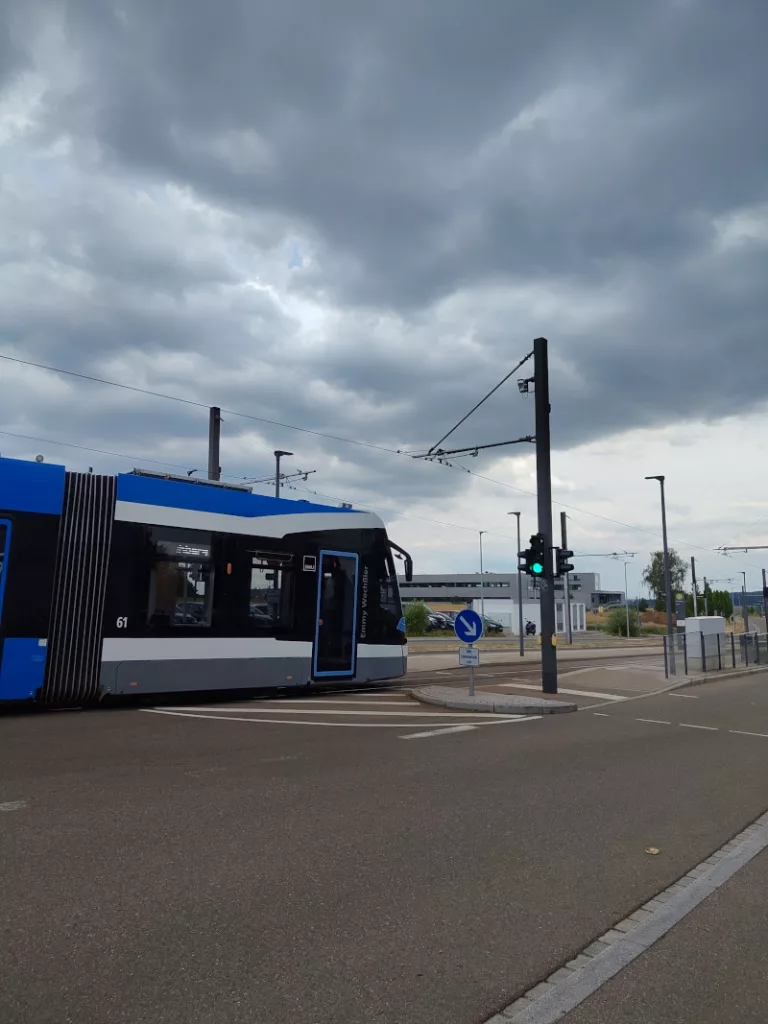 Eine grau-blaue Straßenbahn auf dem Eselsberg im Sience Park vor einem bewölkten Himmel