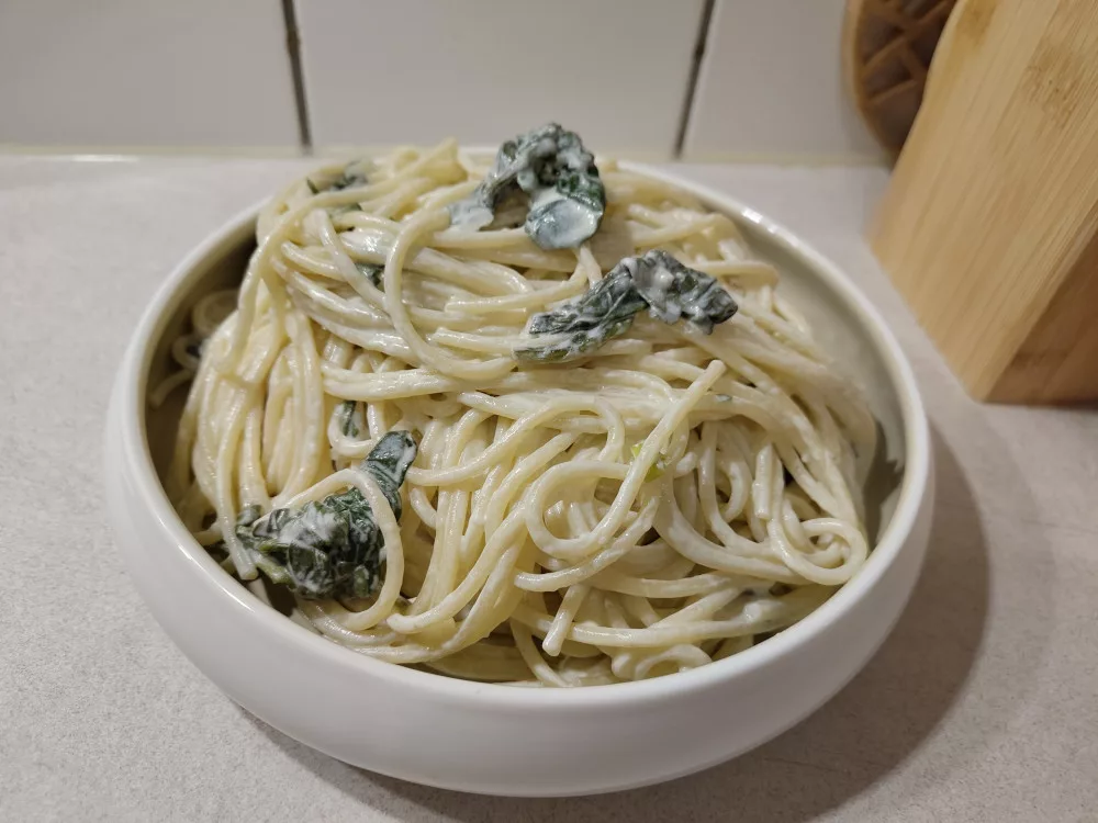 Eine Portion der Pasta mit Ziegenfrischkäse-Spinat Sauce in einem Teller.