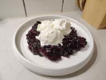 Eine Portion Fruchtkompott aus Apfelbeeren und Birnen auf dem eine größere Portion des Ziegenfrischkäse Eiscreme gegeben wurde.