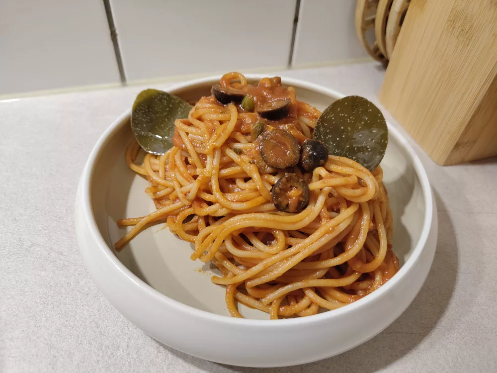 Eine Portion der Pasta puttanesca garniert mit zwei Kapernblätter